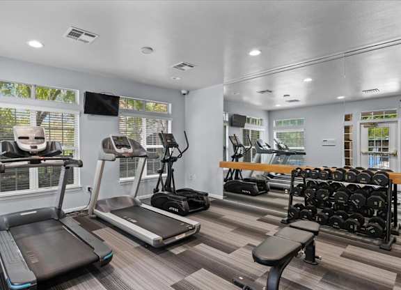 A gym with treadmills, elliptical machines, and dumbbells.at Crowne Chase Apartment Homes, Overland Park, KS, 66210