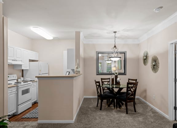 a dining area with a table and chairs and a kitchen in the background at Creekside, Overland Park, Kansas