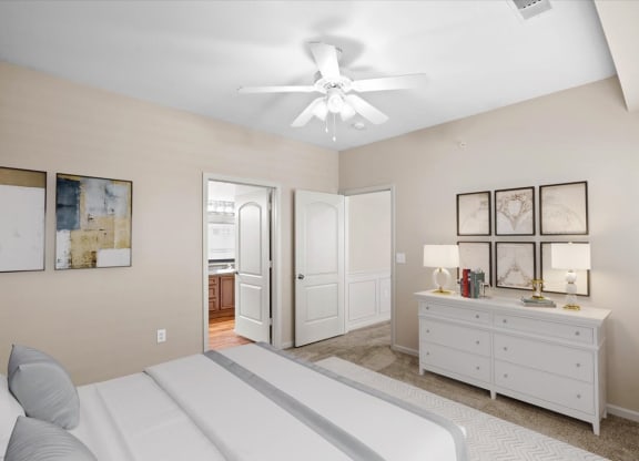 A large bedroom with a ceiling fan and attached master bathroom.