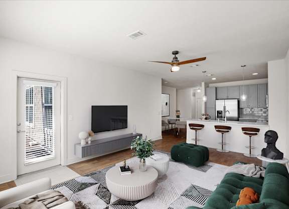 Living room with a ceiling fan, balcony entrance door, hardwood floors, and a modern kitchen in the background.