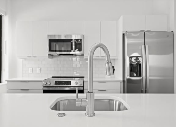 a white kitchen with stainless steel appliances and a sink