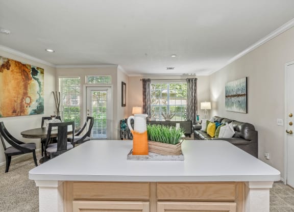 a kitchen with a center island next to a living room with a couch and a table