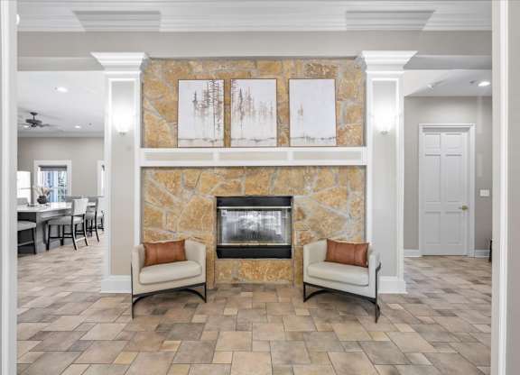 A living room with a stone fireplace and two chairs. at Somerset Oaks Apartment Homes, Olathe, KS