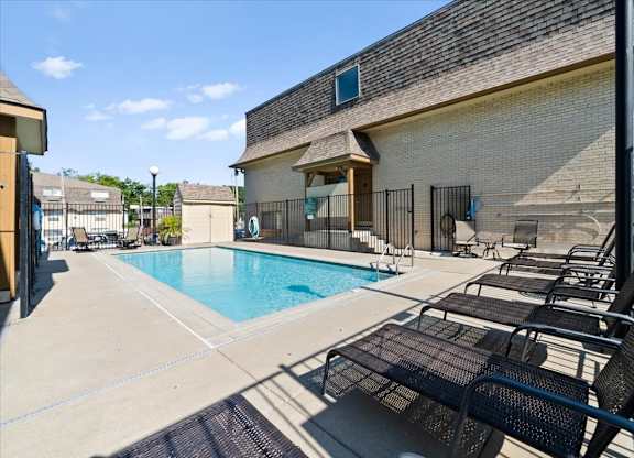 A pool area with lounge chairs and a building in the background. at Malvern Hill Apartment Homes, 66103, KS