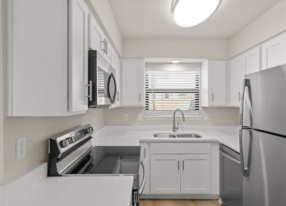 a renovated kitchen with white cabinets and stainless steel appliances