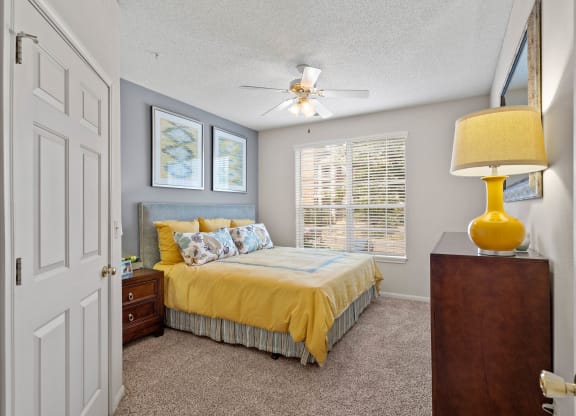 A secondary bedroom with a ceiling fan and large window.