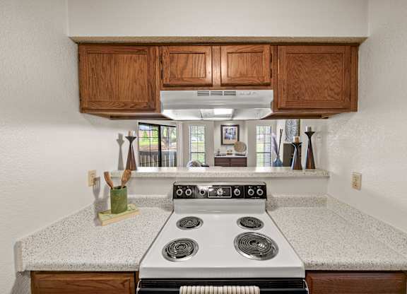 A kitchen with a stove top oven and wooden cabinets.