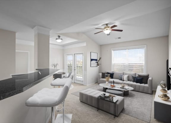 A spacious living room with a ceiling fan, lots of large windows for natural lighting, and barstool seating at the kitchen counters.