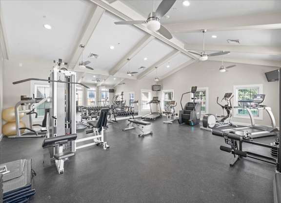 A spacious gym with various exercise equipment and a ceiling fan. at Somerset Oaks Apartment Homes, Olathe, Kansas