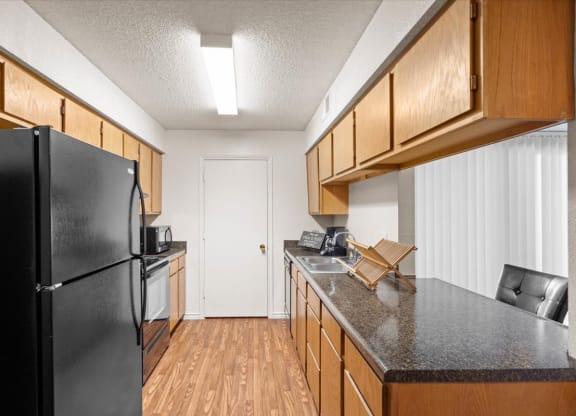 a kitchen with a black refrigerator and a counter top at Wind River Lodge, Lenexa
