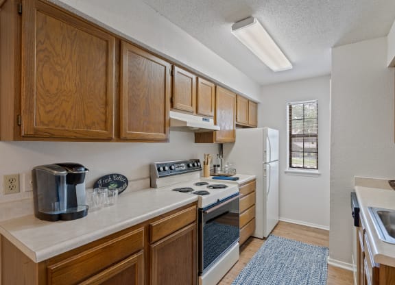a kitchen with a white refrigerator freezer next to a stove top oven at Waterford Place Apartments & Townhomes, Overland Park, KS