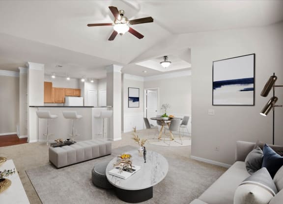 An open living room with a ceiling fan, dining area and barstool seating at the breakfast bar.