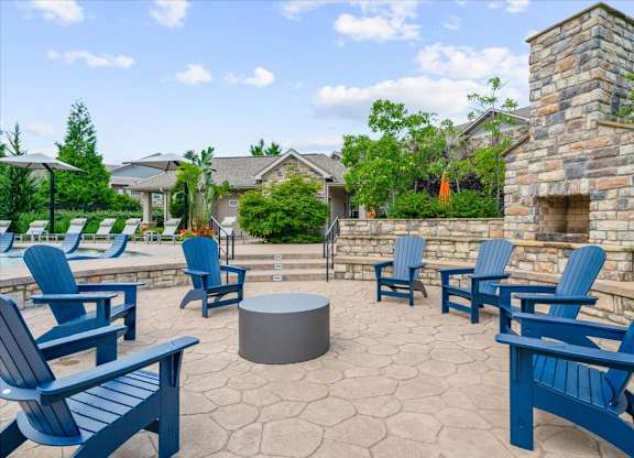 A patio with blue chairs and a fireplace.