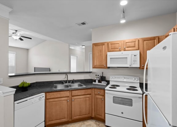 A spacious kitchen with oak cabinets, white appliances, track lighting, and plenty of counterspace.