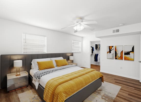 A bedroom with windows, a ceiling fan, and a walk in bedroom closet.