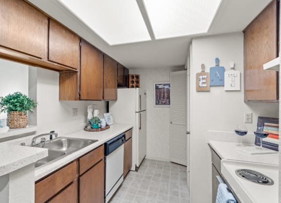 a kitchen with white appliances and wooden cabinets at Pebblebrook, Overland Park