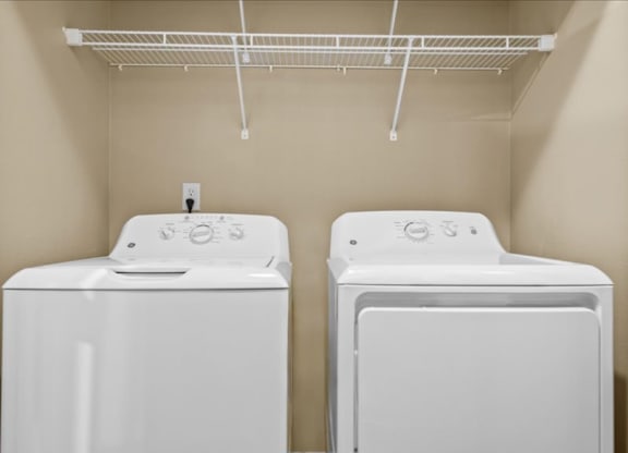 two washers and dryers in a laundry room with a rack on the wall at Avignon Apartment Homes, Olathe, KS, 66062