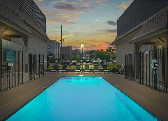 A swimming pool surrounded by a fence and buildings. at Malvern Hill Apartment Homes, 66103, Kansas