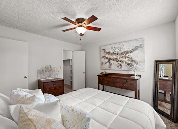 A bedroom with a large bed and a ceiling fan.