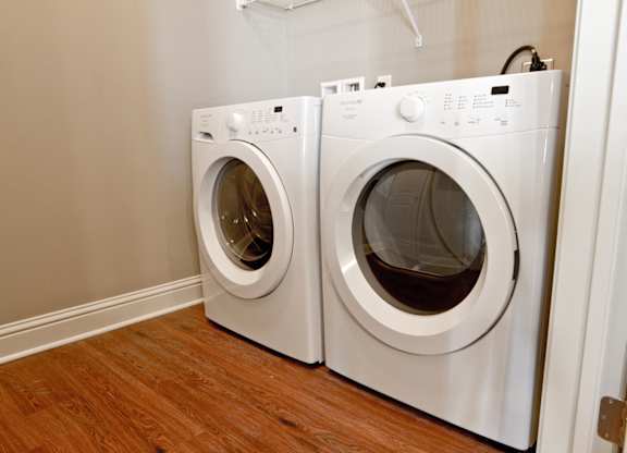 Two white front load washing machines in a laundry room. at Residences at Prairiefire Apartment Homes, Overland Park, KS