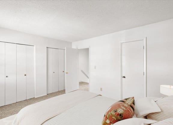 a white bedroom with a large bed and white closets