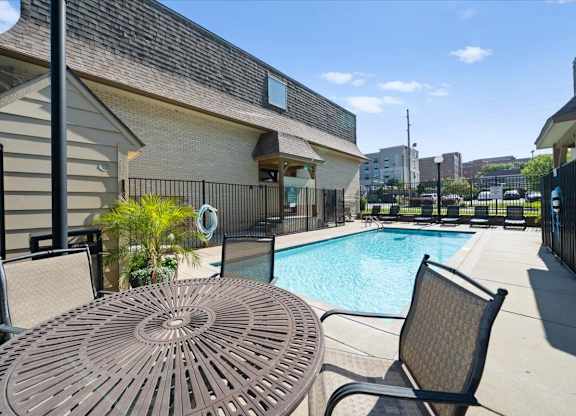A patio with a table and chairs overlooking a pool. at Malvern Hill Apartment Homes, 66103, KS