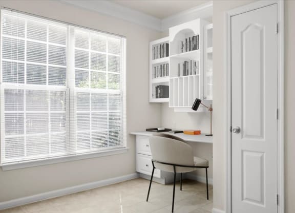 a home office with a desk and a chair in front of a window