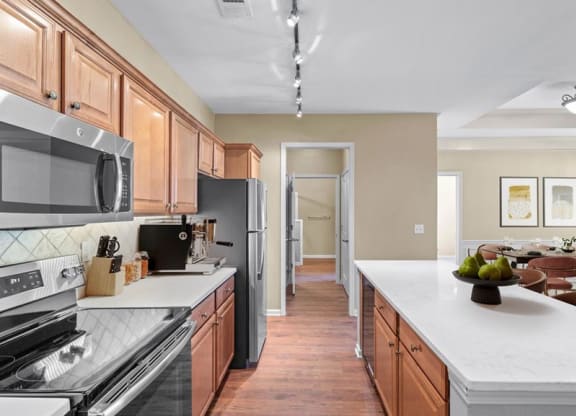 A kitchen with stainless steel appliances, hardwood floors, stone backsplash, quartz countertops and a kitchen island at Avignon Apartments in Olathe, Kansas