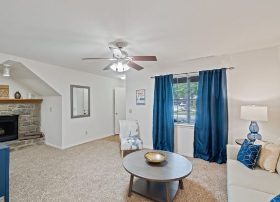 a living room with a fireplace and a ceiling fan at Waterford Place Apartments & Townhomes, Overland Park, 66210