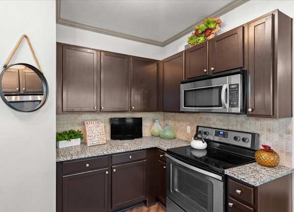 a kitchen with dark cabinets and stainless steel appliances at Stonepost Crossing Apartments, Overland Park, Kansas