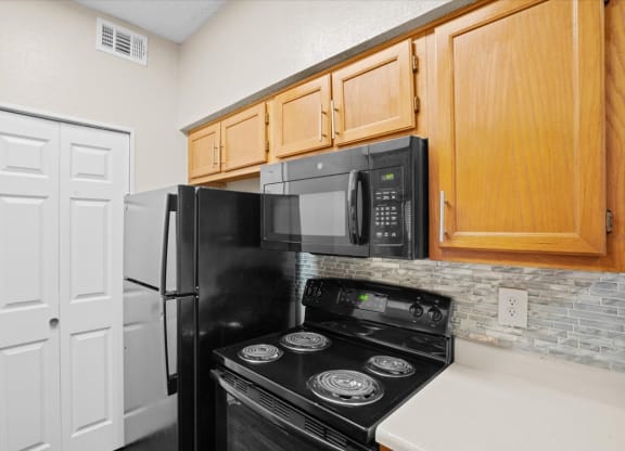 a kitchen with a stove top oven next to a refrigerator at Creekview Apartment Homes, Texas