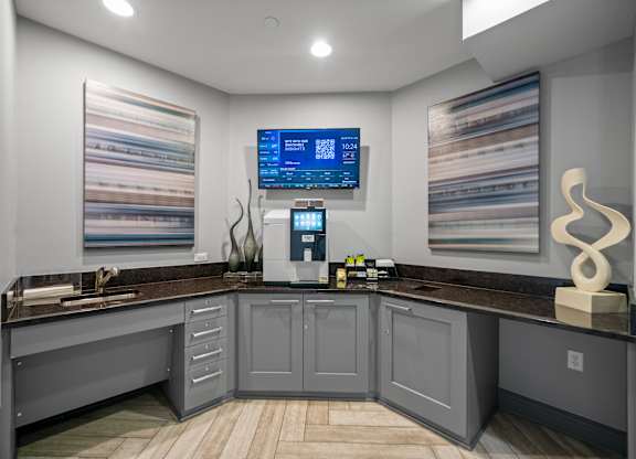A modern kitchen with a wooden floor and grey cabinets.