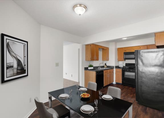 a kitchen and dining room with a black table and chairs at Deerfield Apartments, Olathe, Kansas, 66062