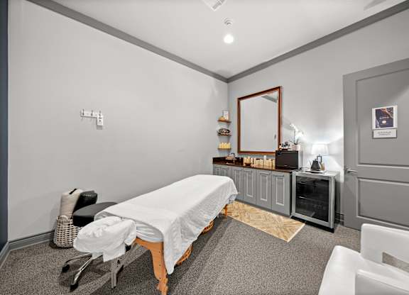 A room with a massage table and a mirror on the wall.