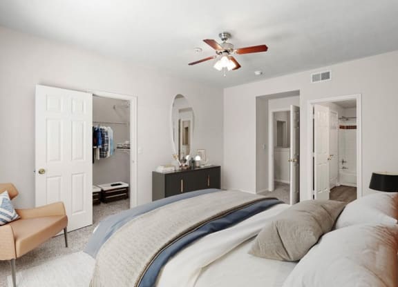 A bedroom with a ceiling fan, large walk in closet, and an attached master bathroom.