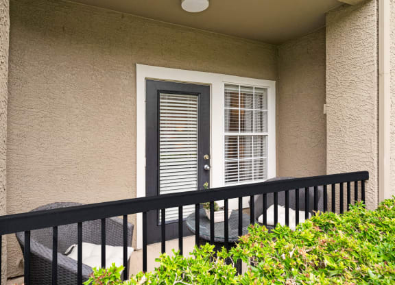 a balcony with two chairs and a door