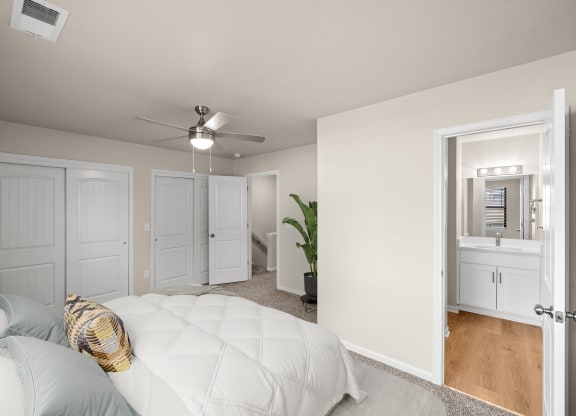 a bedroom with a white bed and a ceiling fan