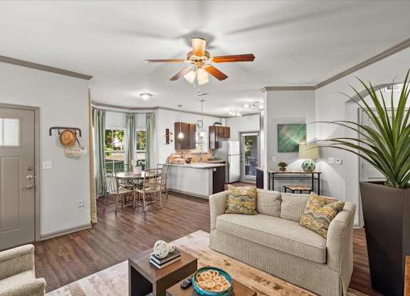 a living room with a couch a table and a ceiling fan at Stonepost Crossing Apartments, Overland Park
