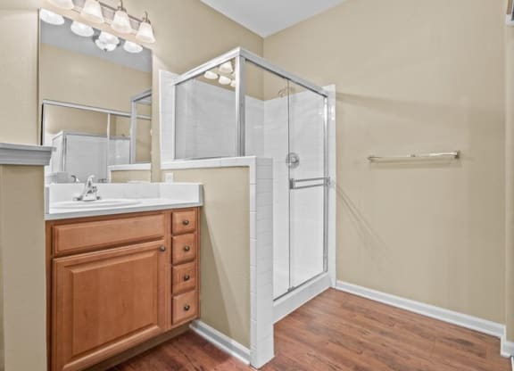 A bathroom with a large mirror, quartz countertops and a shower at Avignon Apartments in Olathe, Kansas