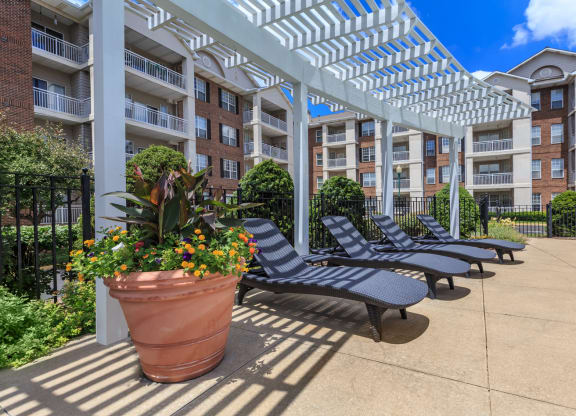 Lounge chairs in the courtyard by the outdoor swimming pool at The Claremont Apartments in Overland Park, KS.