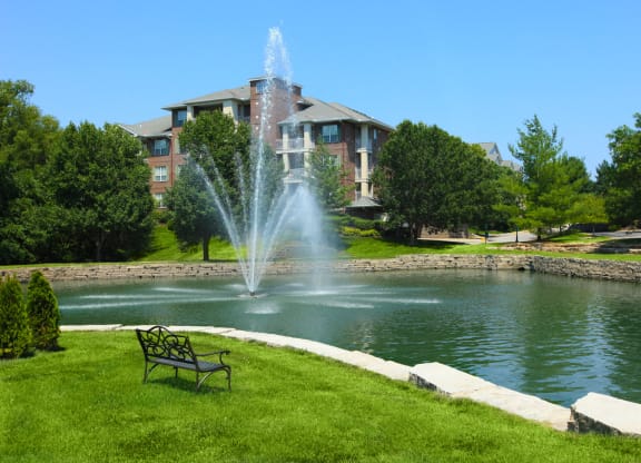 Stunning water fountain  and bench at the community lake at The Claremont Apartments in Overland Park, Kansas.