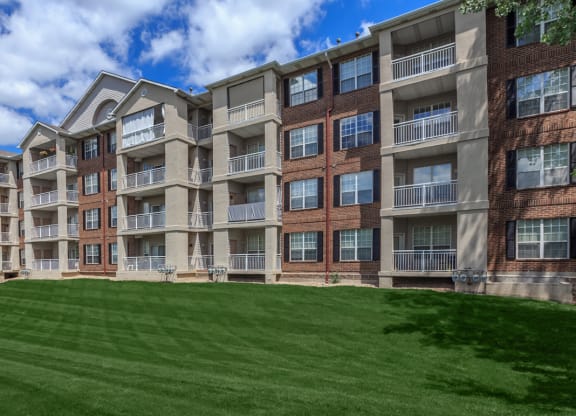 A large apartment building sitting over a lush landscape lawn.