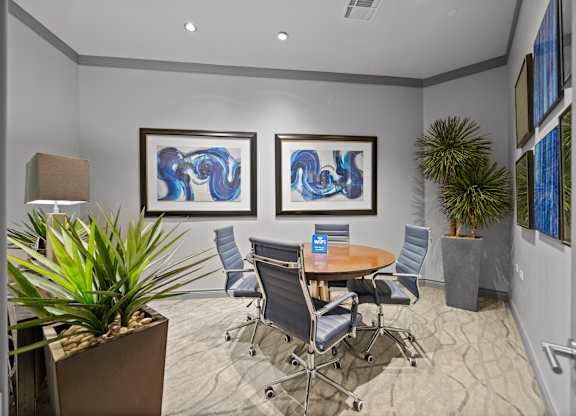A conference room with a table, chairs, and two framed artworks on the wall.
