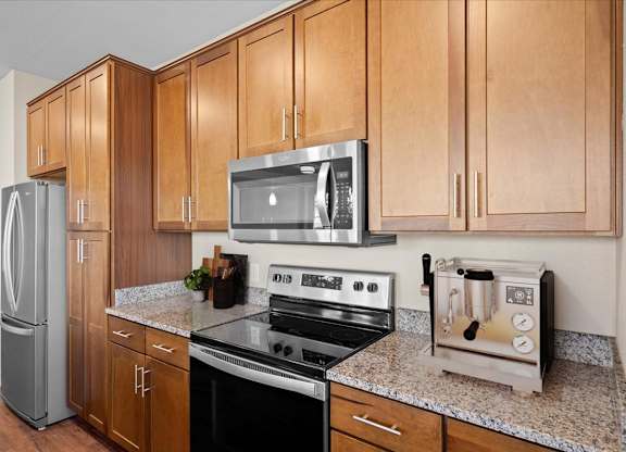 a kitchen with a stove top oven next to a refrigerator at The Dorset, Kansas City, 64112