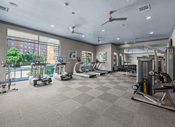 A spacious gym with a variety of equipment and a view of a city skyline.