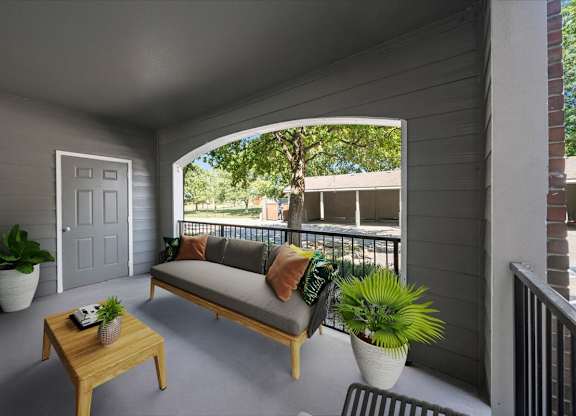 A balcony with a sofa, table, and potted plants. at Somerset Oaks Apartment Homes, Olathe, KS, 66062