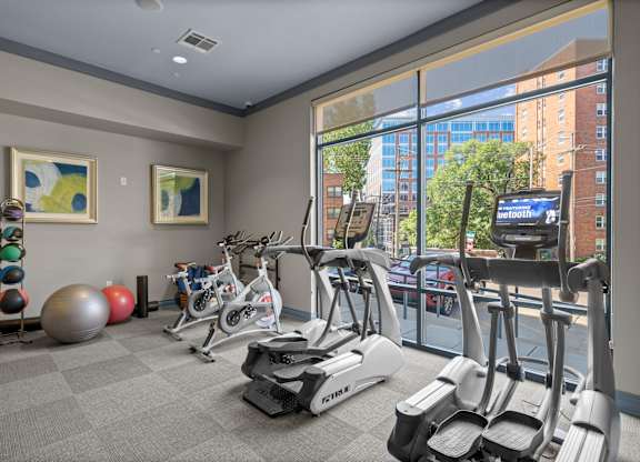 A gym with a row of treadmilers and exercise balls.