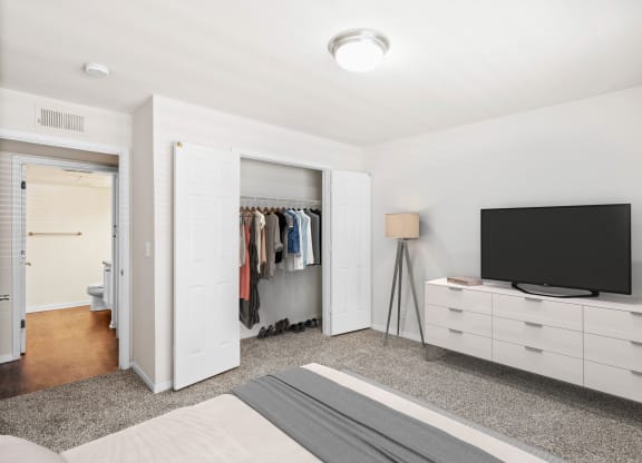 a bedroom with a bed and a dresser with a tv on top of itat Stonebriar Woods Apartments, Overland Park, 66213