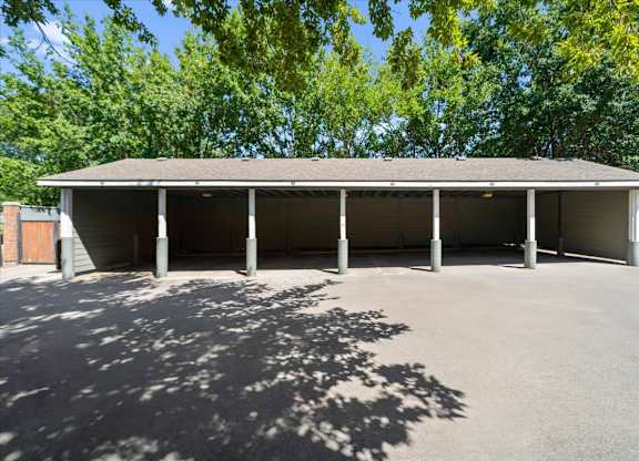 A large building with a grey roof and pillars is surrounded by trees. at Somerset Oaks Apartment Homes, Olathe 66062