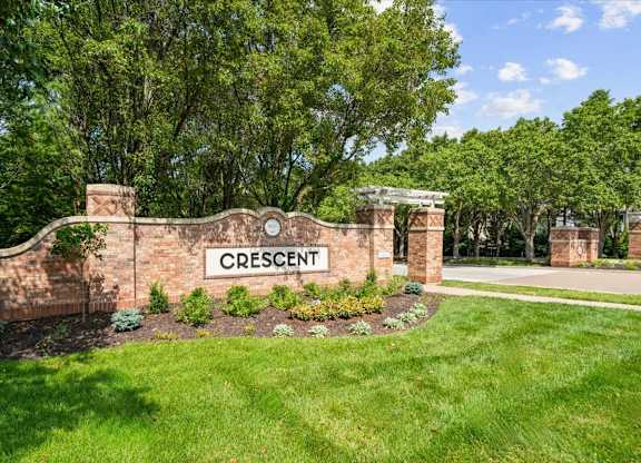 A sign that says Crescent in front of a green lawn.